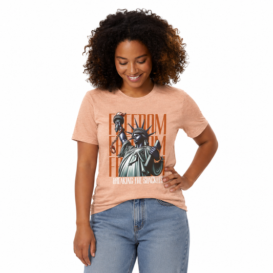 Woman wearing a peach t-shirt with a graphic design of the Statue of Liberty and text.