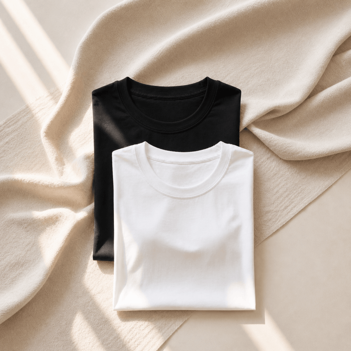 Neutral folded t-shirts in black and white on linen background