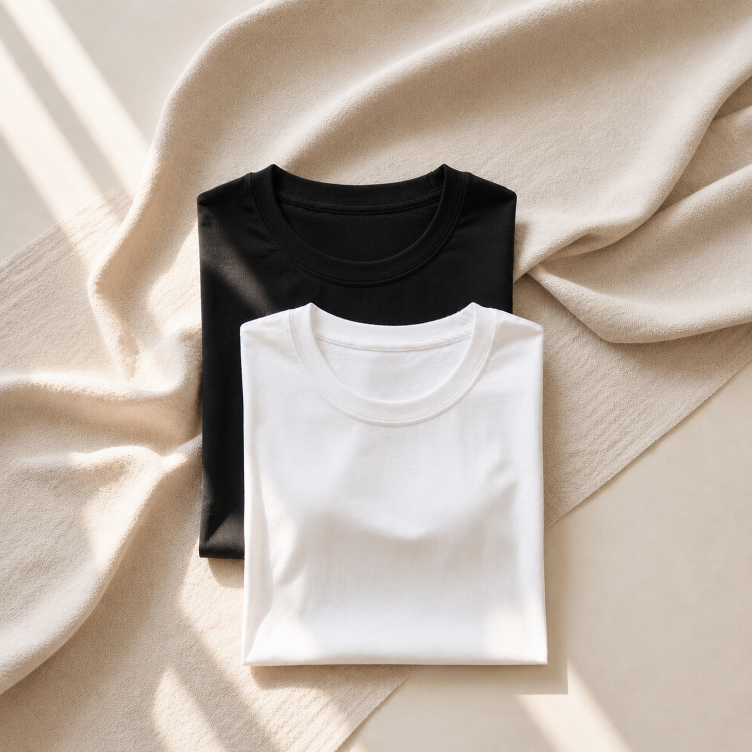 Neutral folded t-shirts in black and white on linen background