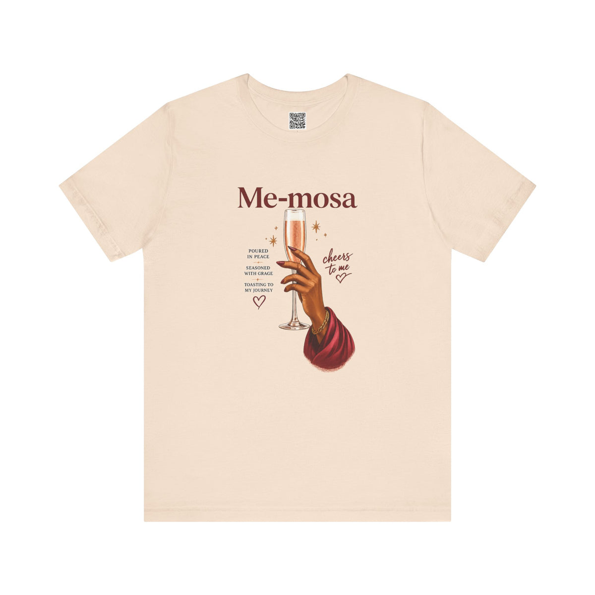 A light beige crewneck t-shirt featuring a graphic print of a hand holding a champagne flute with the text 'Me-mosa' and 'cheers to me' on a solid white background.