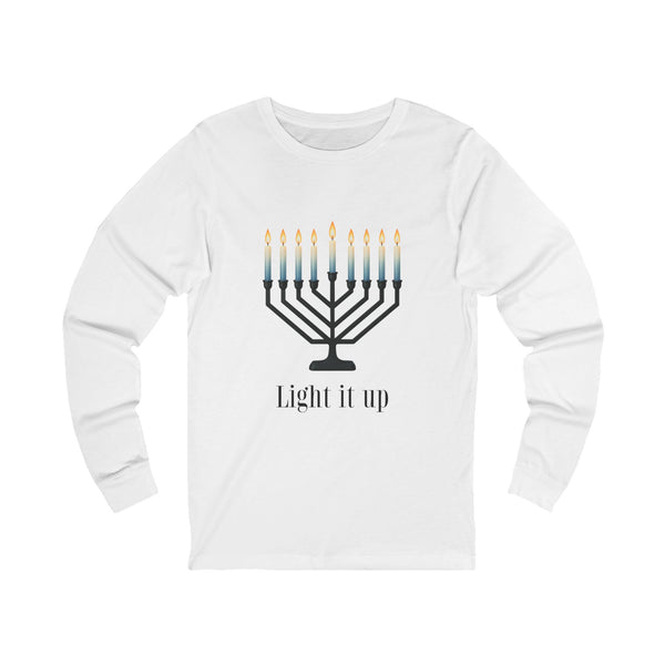A white long-sleeve t-shirt with a graphic of a black menorah with blue-to-yellow lit candles and the text 'Light it up' printed below, displayed on a clean white background.