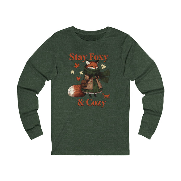 A dark heather green long-sleeve t-shirt featuring a graphic of a cozy fox wearing a green scarf and brown coat, surrounded by autumn leaves, with the text 'Stay Foxy & Cozy' in orange.
