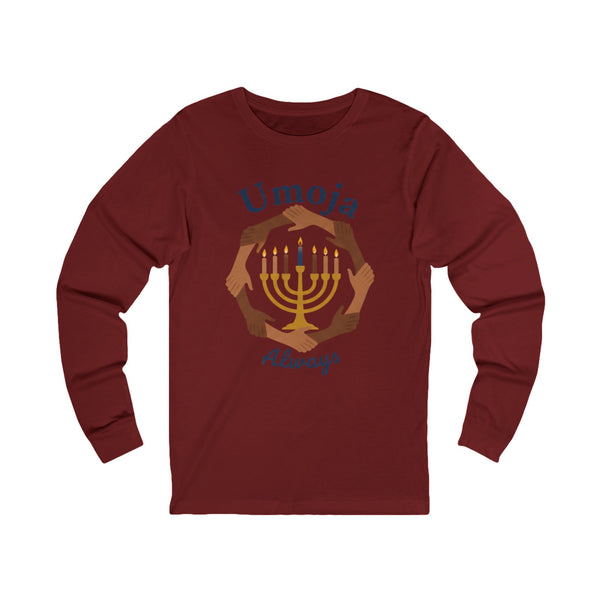 A maroon long-sleeve t-shirt with a graphic print of a golden menorah surrounded by diverse hands, with the text 'Umoja Always' in blue script.