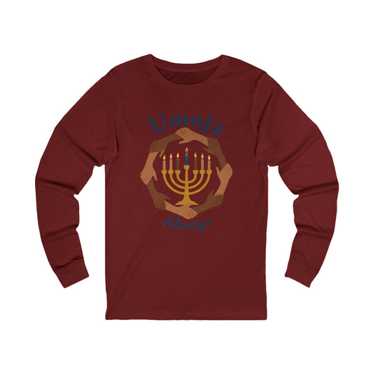 A maroon long-sleeve t-shirt with a graphic print of a golden menorah surrounded by diverse hands, with the text 'Umoja Always' in blue script.