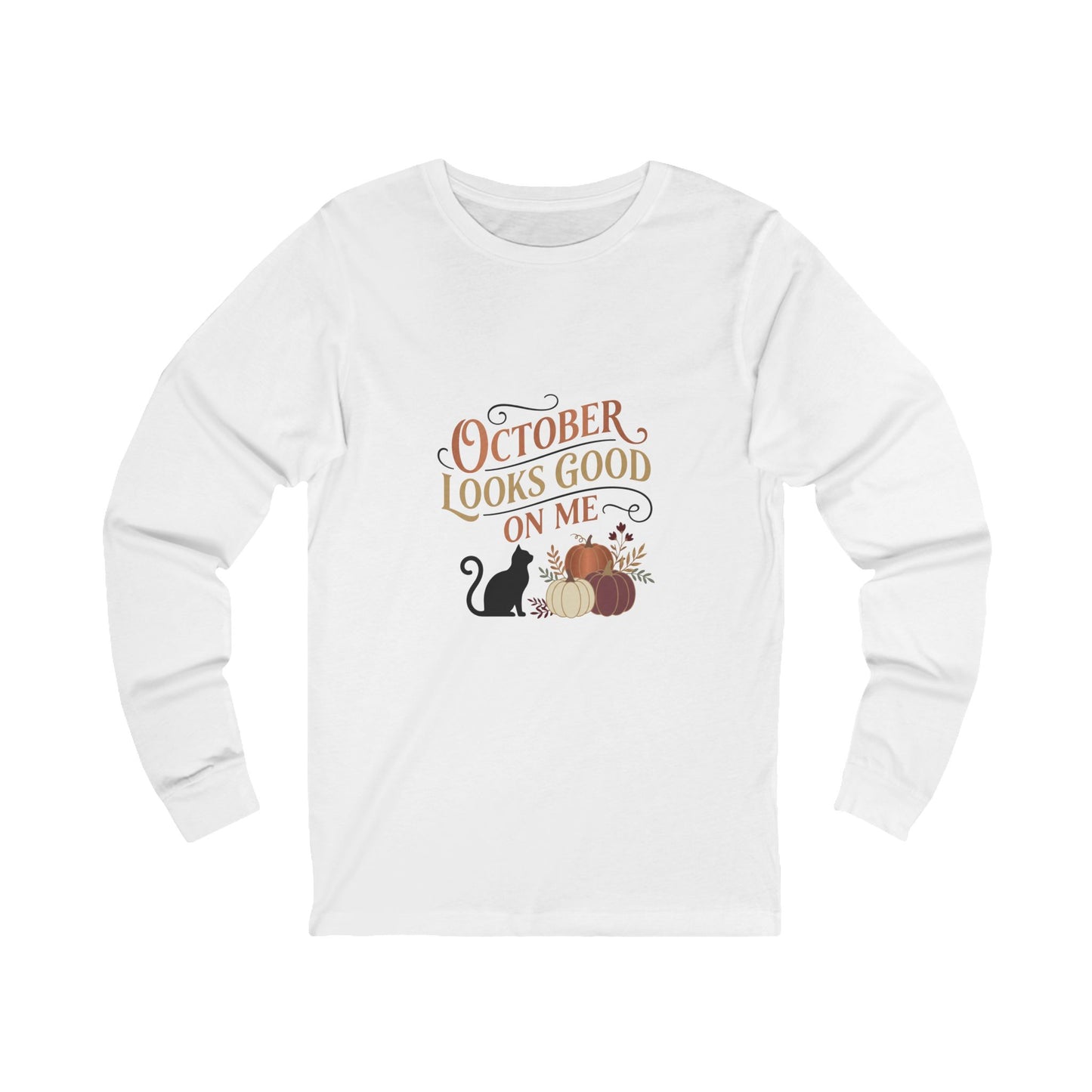 A white long-sleeve t-shirt with a graphic on the front that reads 'OCTOBER LOOKS GOOD ON ME' in brown and orange lettering, accompanied by a black cat, pumpkins, and autumn leaves.