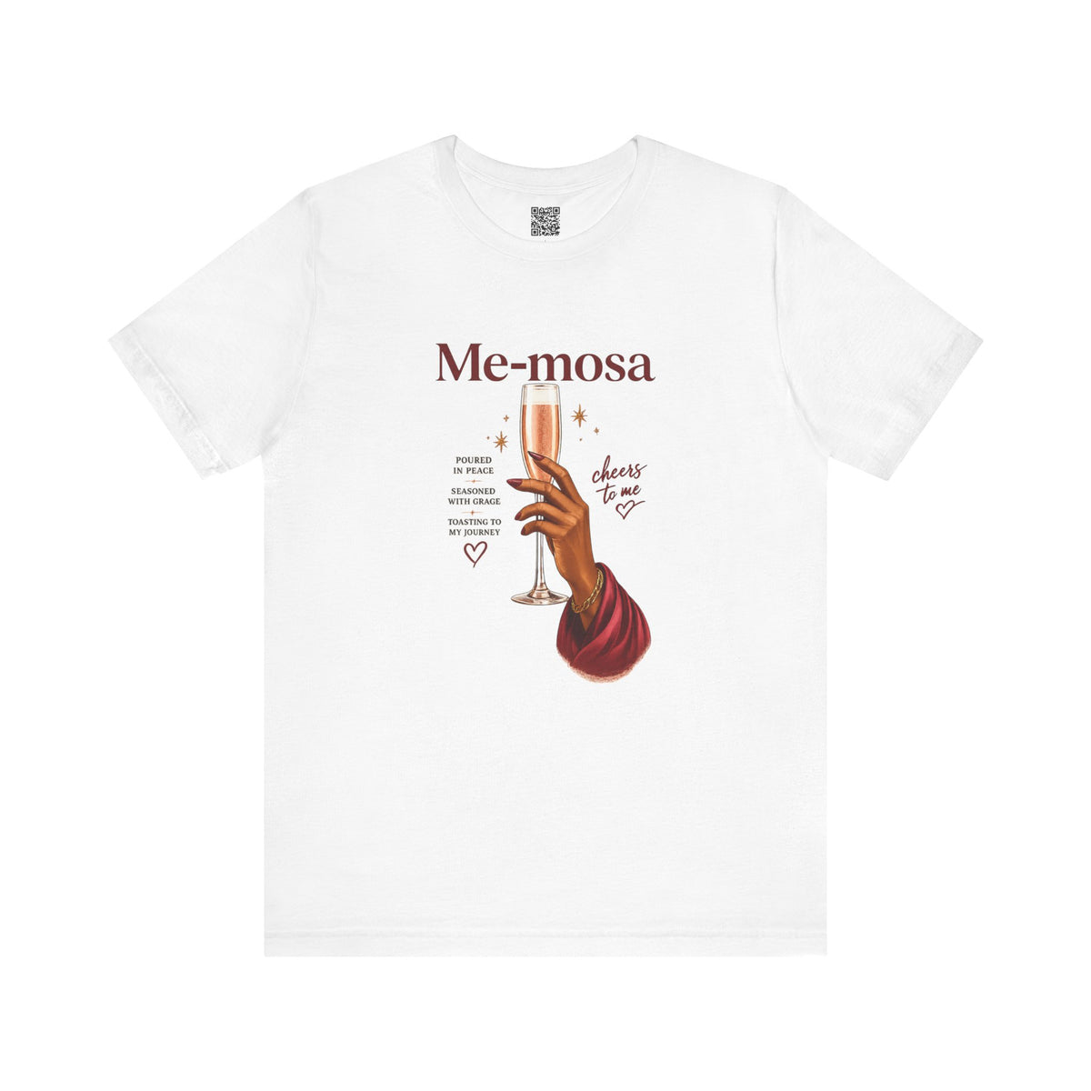 A white short-sleeve crewneck t-shirt featuring a graphic print on the front. The print displays the text 'Me-mosa' in a dark reddish-brown serif font, above an illustration of a hand holding a champagne flute with pink champagne, surrounded by small decorative text and hearts.