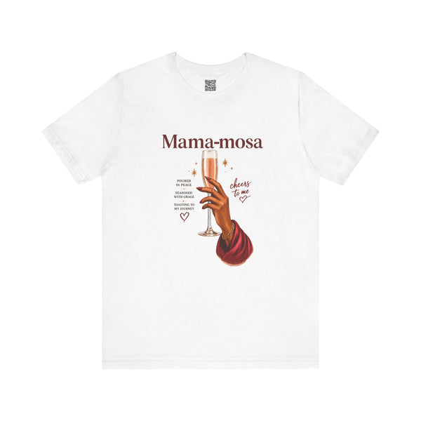 A white short-sleeve crewneck t-shirt featuring a graphic print of a hand holding a champagne flute with the text 'Mama-mosa' and 'cheers to me' in a vintage style.