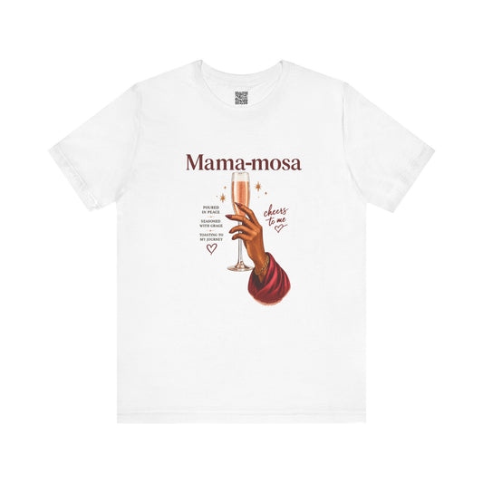 A white short-sleeve crewneck t-shirt featuring a graphic print of a hand holding a champagne flute with the text 'Mama-mosa' and 'cheers to me' in a vintage style.