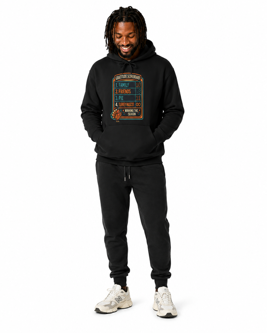 Gratitude Scoreboard Thanksgiving football hoodie in black with turkey game-day graphic with white background on a male model wearing joggers and tennis shoes.