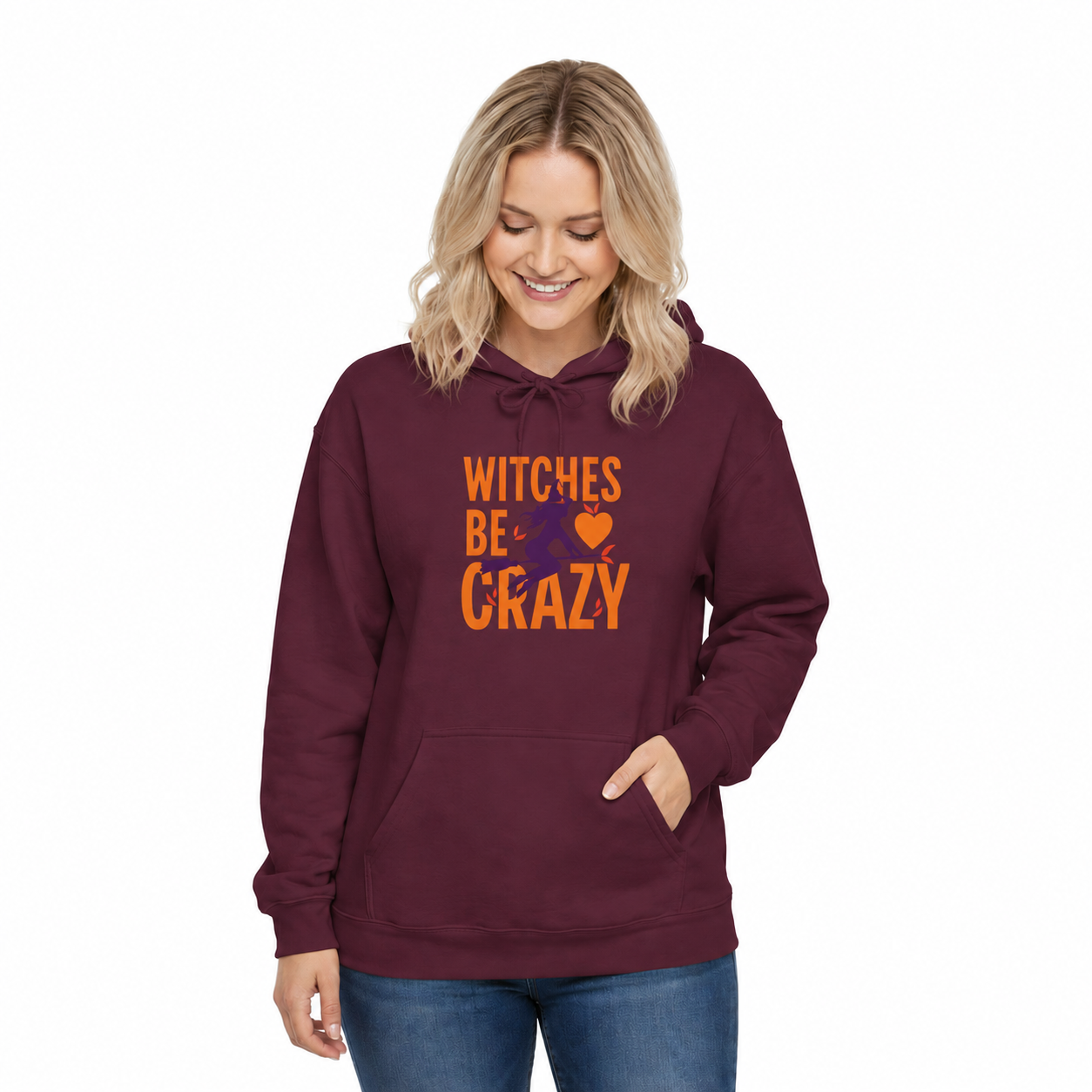 A woman wearing a maroon pullover hoodie with the text 'WITCHES BE CRAZY' and a small orange heart graphic on the front, paired with blue jeans against a plain white background.