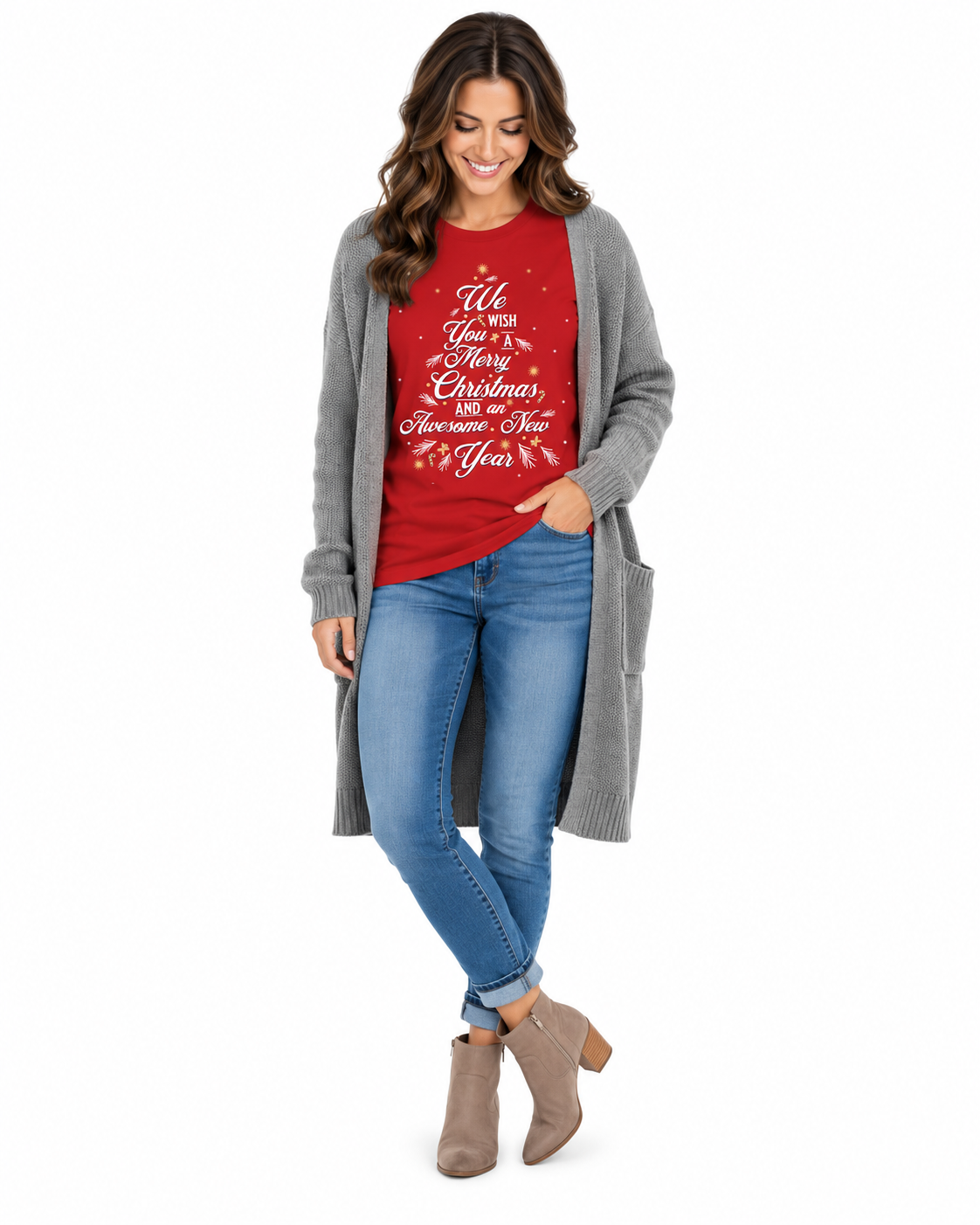 A woman modeling a festive holiday outfit featuring a red crewneck t-shirt with white cursive Christmas text, layered under a long gray knit cardigan, paired with blue jeans and taupe ankle boots, on a solid white background.