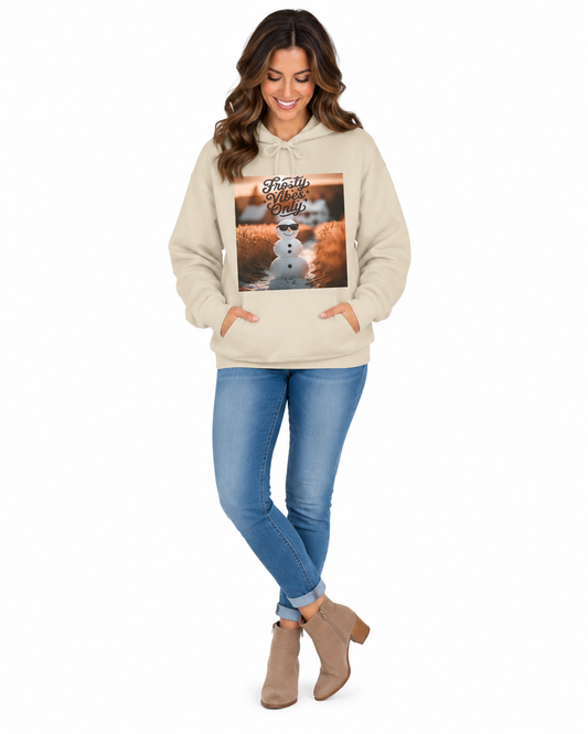 A woman modeling a beige pullover hoodie with a large square graphic print on the front, paired with blue jeans and tan ankle boots, against a plain white background.
