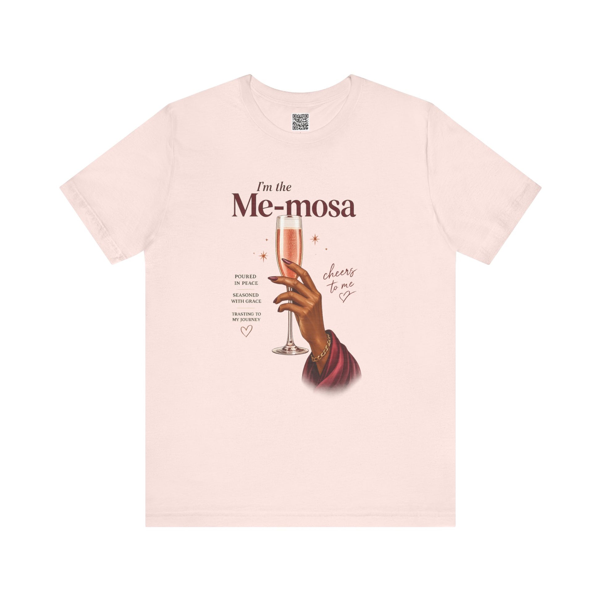 Soft pink t-shirt with a graphic of a hand holding a glass of mimosas and text on a white background