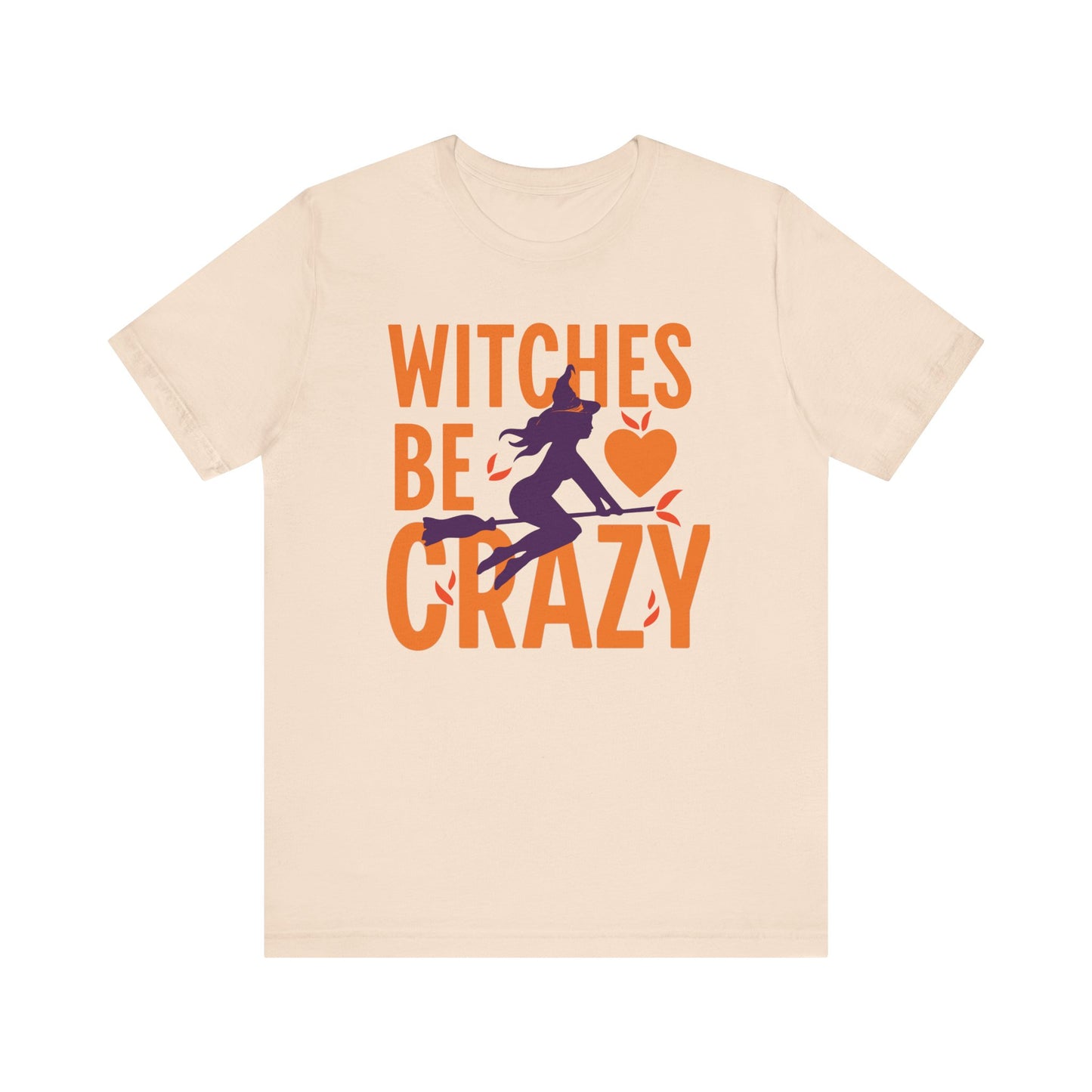 A light beige crewneck t-shirt featuring a Halloween graphic on the front with the text 'WITCHES BE CRAZY' in orange, a purple witch silhouette, and an orange heart.