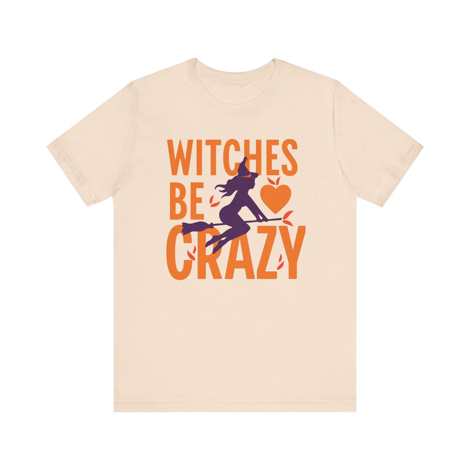 A light beige crewneck t-shirt featuring a Halloween graphic on the front with the text 'WITCHES BE CRAZY' in orange, a purple witch silhouette, and an orange heart.