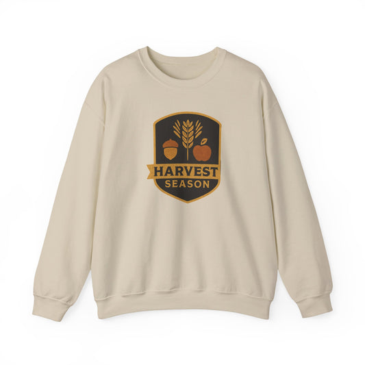 A light beige crewneck sweatshirt with a 'Harvest Season' graphic on the chest, featuring an acorn, wheat stalk, and pumpkin in autumn colors.