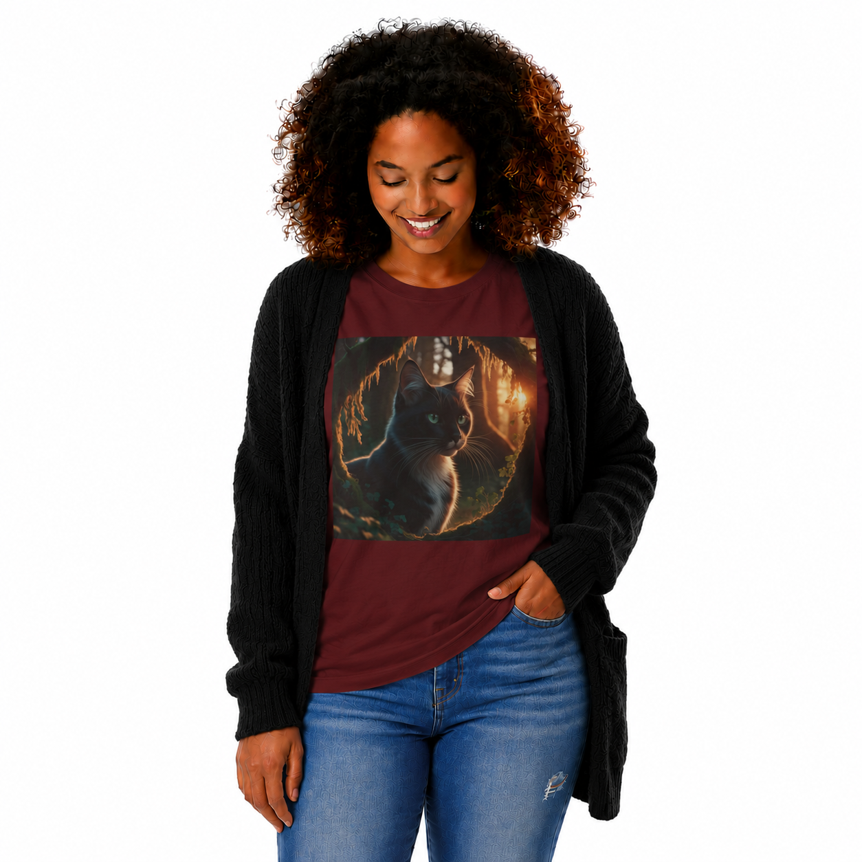A woman with curly hair wearing a maroon graphic t-shirt with a black cat print, a black cardigan, and blue jeans, standing against a plain white background.